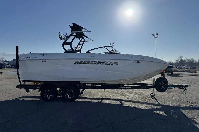 Slide: The Image of 2026 Moomba Craz boat on trailer under bright sun in parking lot. - 6