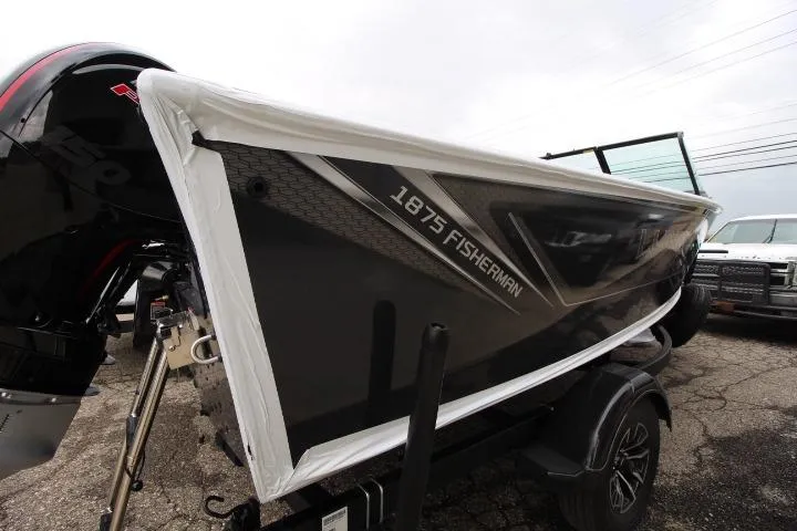 Slide: The Image of 2026 Lund 1875 Fisherman boat on trailer, black exterior, partially covered, parked outdoors. - 4