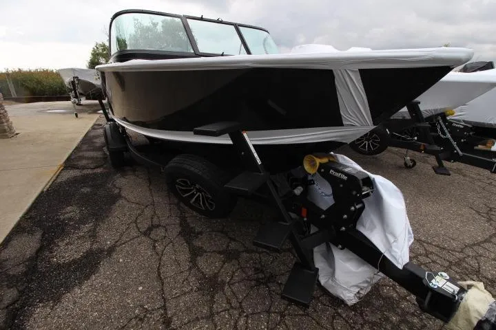 Slide: The Image of 2026 Lund 1875 Fisherman boat on trailer, black exterior, parked on cracked pavement. - 5
