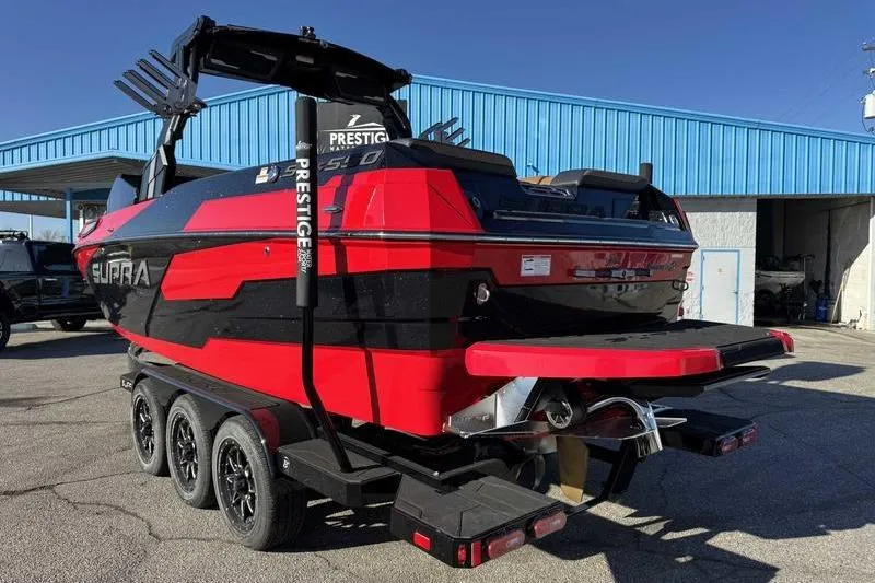 Slide: The Image of 2025 Supra SE boat in red and black, parked on a trailer outside a blue building. - 3