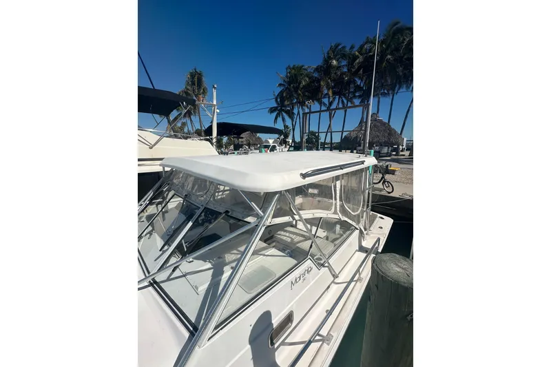 Slide: The Image of 2002 Mainship Pilot 34 boat docked under clear blue sky with palm trees. - 10