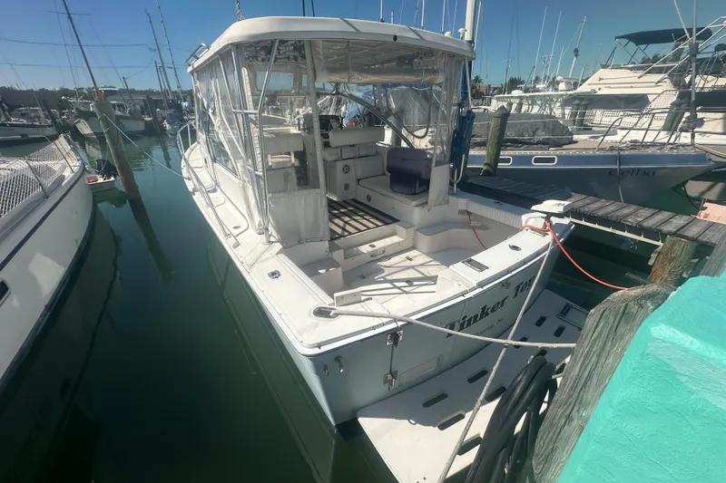 Slide: The Image of 2002 Mainship Pilot 34 docked at a marina, featuring a covered cockpit and clear skies. - 2