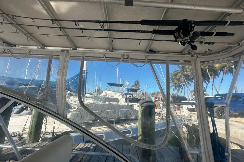 Slide: The Image of 2002 Mainship Pilot 34 interior view with fishing rods, docked near palm trees. - 30