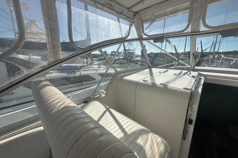 Slide: The Image of 2002 Mainship Pilot 34 cockpit with white seating and clear windows, docked at marina. - 35