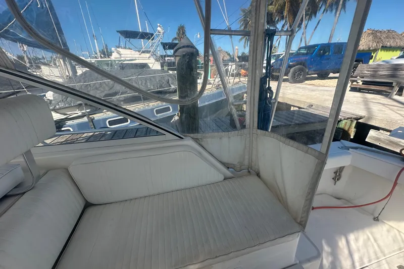 Slide: The Image of 2002 Mainship Pilot 34 interior with white seating, docked near other boats and palm trees. - 38