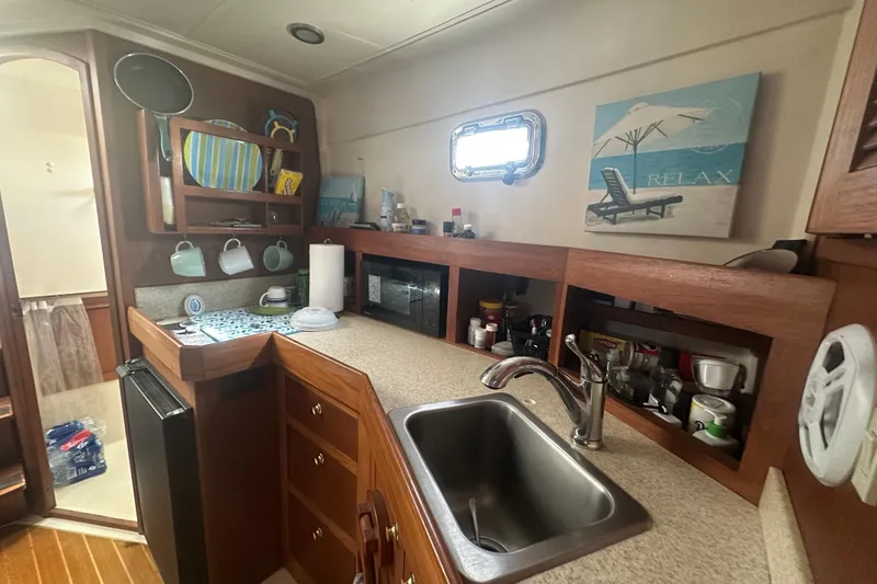 Slide: The Image of 2002 Mainship Pilot 34 boat kitchen with sink, cabinets, and relaxing decor. - 44