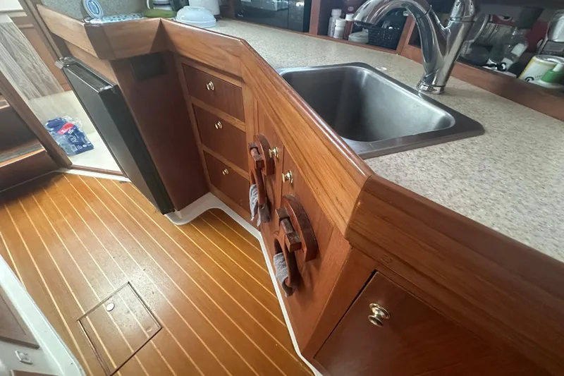 Slide: The Image of 2002 Mainship Pilot 34 boat interior with wooden cabinetry and stainless steel sink. - 45