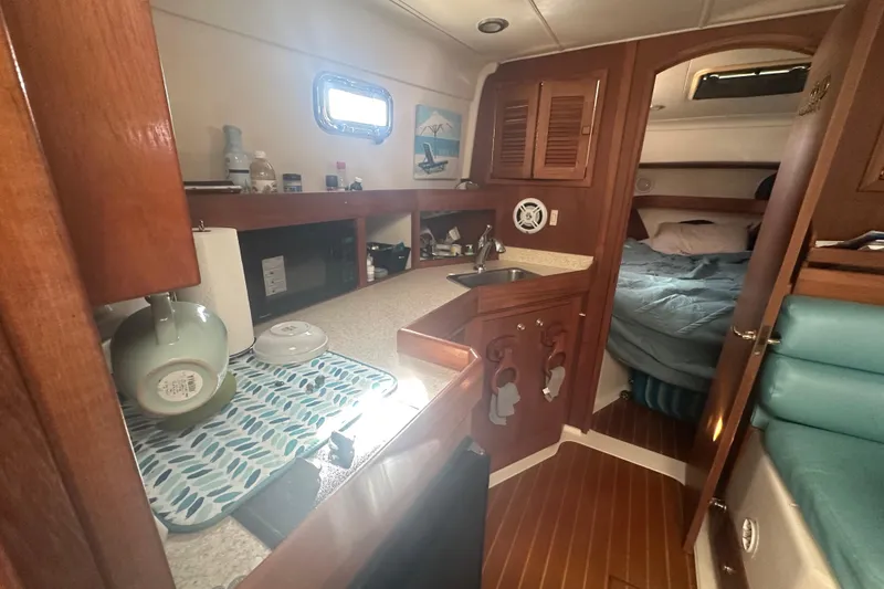 Slide: The Image of 2002 Mainship Pilot 34 interior with kitchenette, sink, and cozy sleeping area. - 46