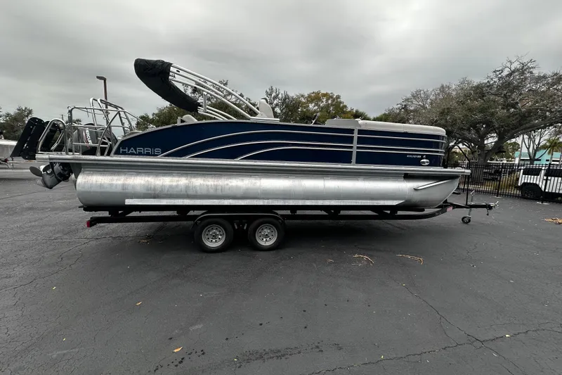 The Image of 2025 Harris Sunliner 230 pontoon boat on trailer, parked outdoors. - 1