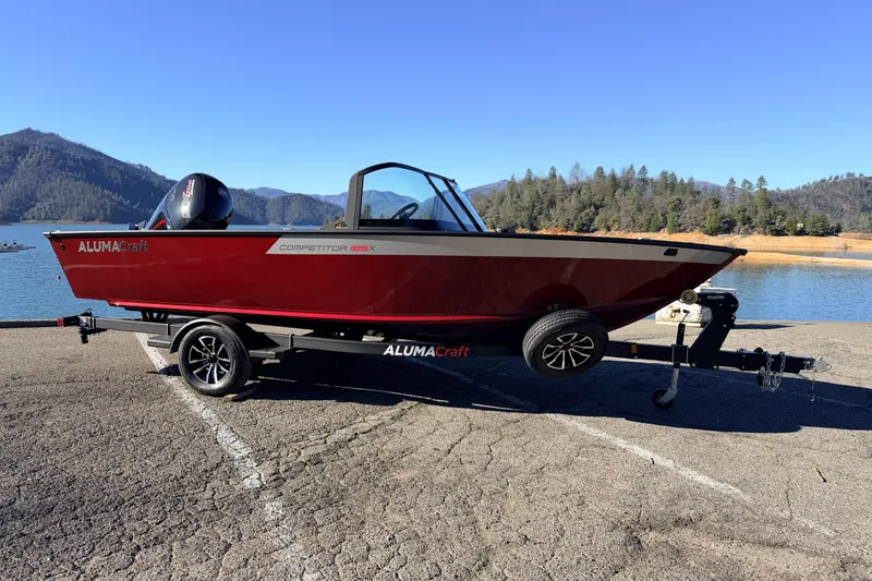 Slide: The Image of 2025 Alumacraft Competitor 185X Sport boat on trailer by scenic lake and mountains. - 12