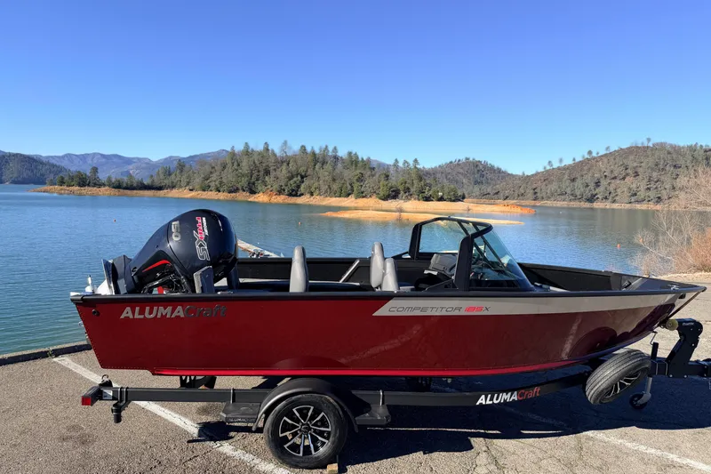 Slide: The Image of 2025 Alumacraft Competitor 185X Sport boat by a scenic lake with mountains. - 13
