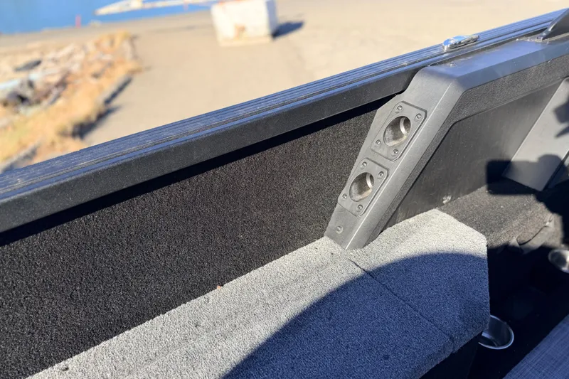 Slide: The Image of 2025 Alumacraft Competitor 185X Sport interior detail with rod holder, dock in background. - 35