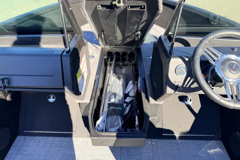 Slide: The Image of 2025 Alumacraft Competitor 185X Sport boat interior with open storage compartment and steering wheel. - 40