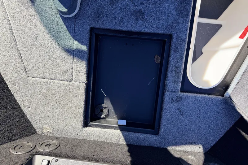 Slide: The Image of 2025 Alumacraft Competitor 185X Sport boat interior with storage compartment and carpeted flooring. - 44