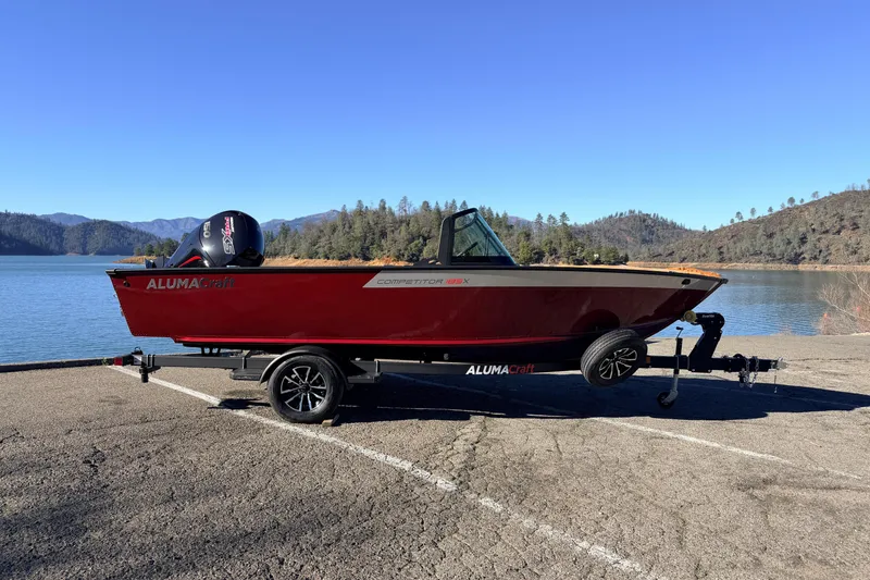 Slide: The Image of 2025 Alumacraft Competitor 185X Sport boat on trailer by scenic lake. - 6