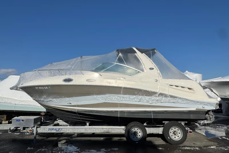 The Image of 2006 Sea Ray Sundancer 280 boat on trailer, covered in protective wrap, under clear blue sky. - 1