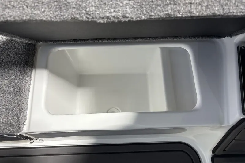 Slide: The Image of 2026 Phoenix 20 XE boat storage compartment with gray carpeted edges. - 18
