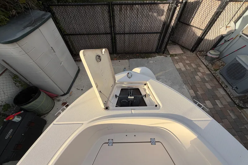 Slide: The Image of 2018 Robalo R180 Center Console boat with open storage compartment, docked in a fenced area. - 14
