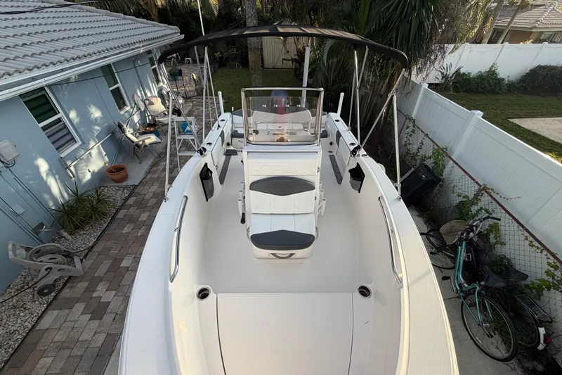 Slide: The Image of 2018 Robalo R180 Center Console boat docked beside a house, featuring a spacious deck. - 15