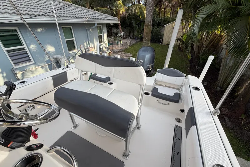 Slide: The Image of 2018 Robalo R180 Center Console boat with seating and steering wheel in a backyard setting. - 17