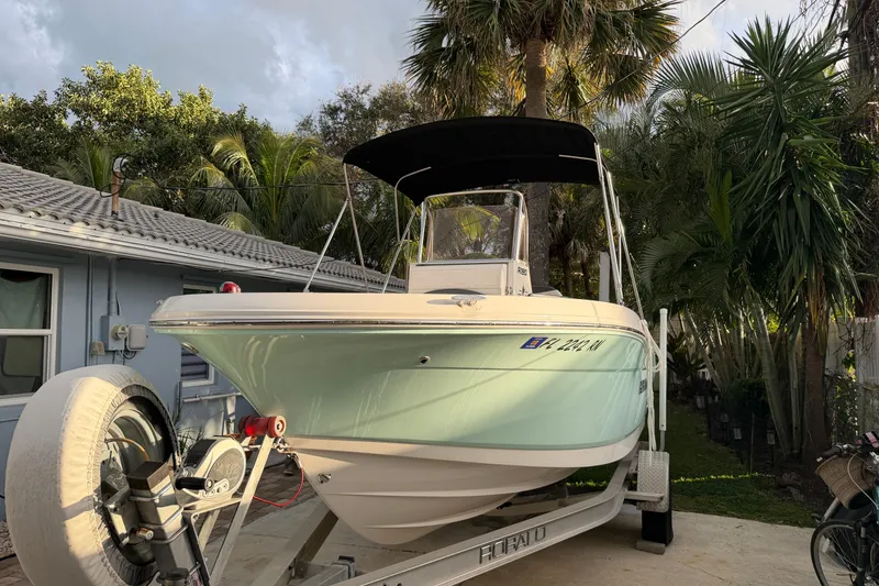 Slide: The Image of 2018 Robalo R180 Center Console boat on trailer, surrounded by tropical foliage. - 2