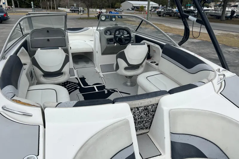 Slide: The Image of 2006 Yamaha Boats SX230 HO interior with seating and steering wheel, docked outdoors. - 24