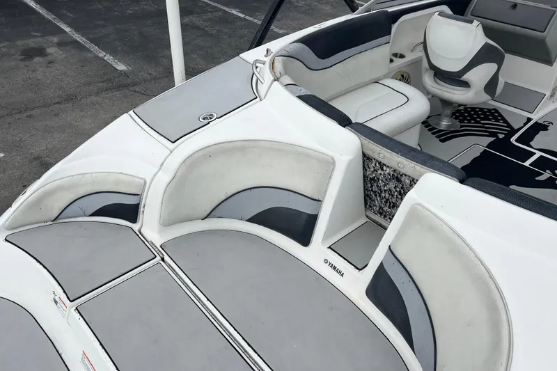 Slide: The Image of 2006 Yamaha Boats SX230 HO interior with white and gray seating, parked on pavement. - 26