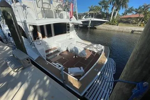 Slide: The Image of 1987 Topaz 44 Flybridge yacht docked by a canal with palm trees. - 2