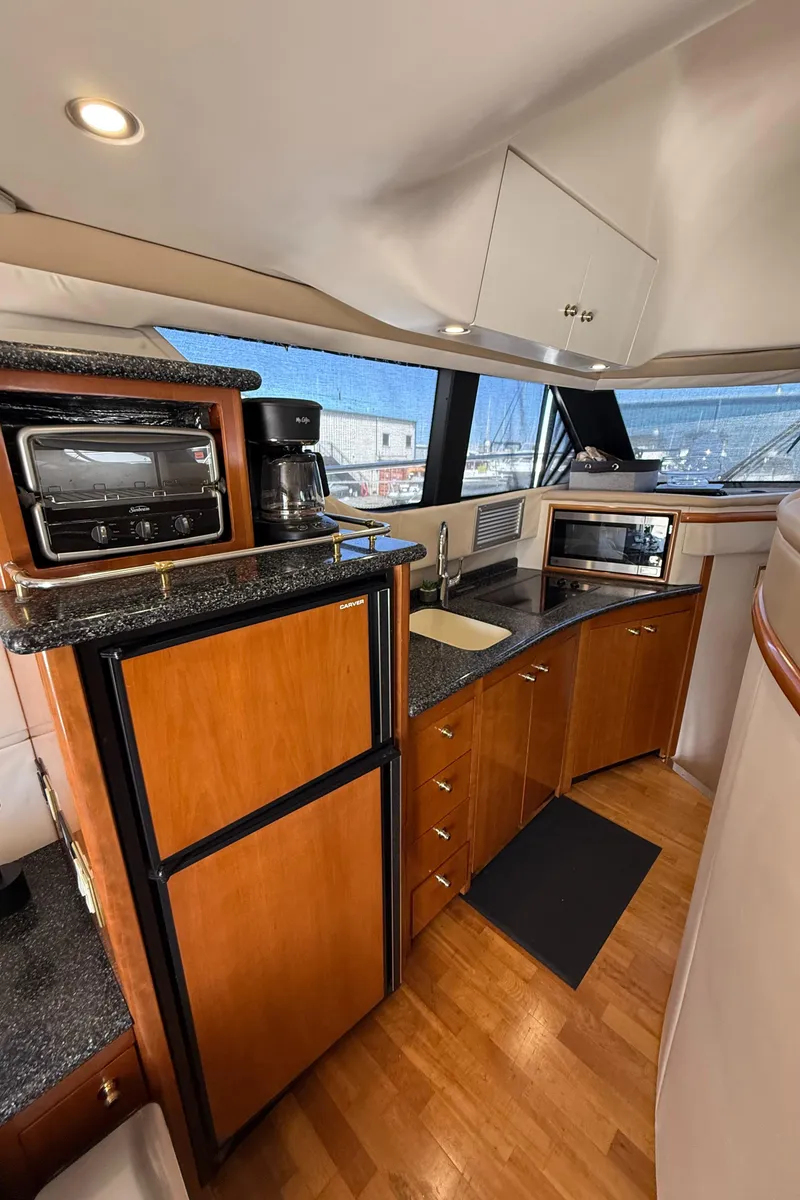 Slide: The Image of 2000 Carver 450 Voyager Pilothouse kitchen with wood cabinets and modern appliances. - 21