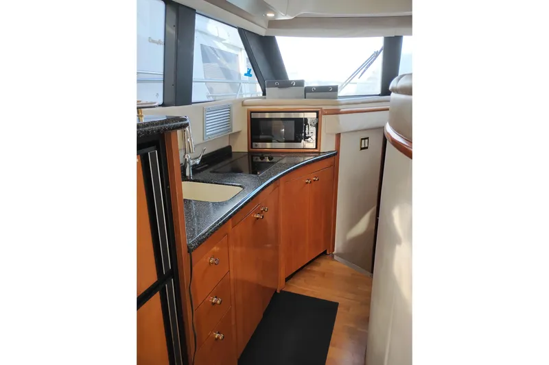 Slide: The Image of 2000 Carver 450 Voyager Pilothouse kitchen with wood cabinetry and modern appliances. - 22