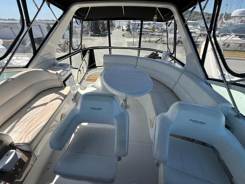 Slide: The Image of 2000 Carver 450 Voyager Pilothouse interior with seating and table, docked at marina. - 34