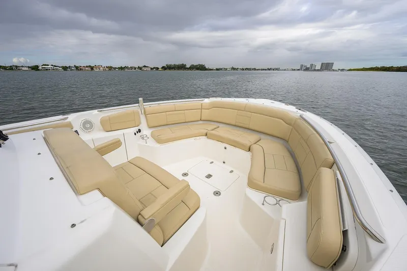 Slide: The Image of 2019 Pursuit S 328 Sport boat with spacious beige seating, on calm waters under cloudy skies. - 15