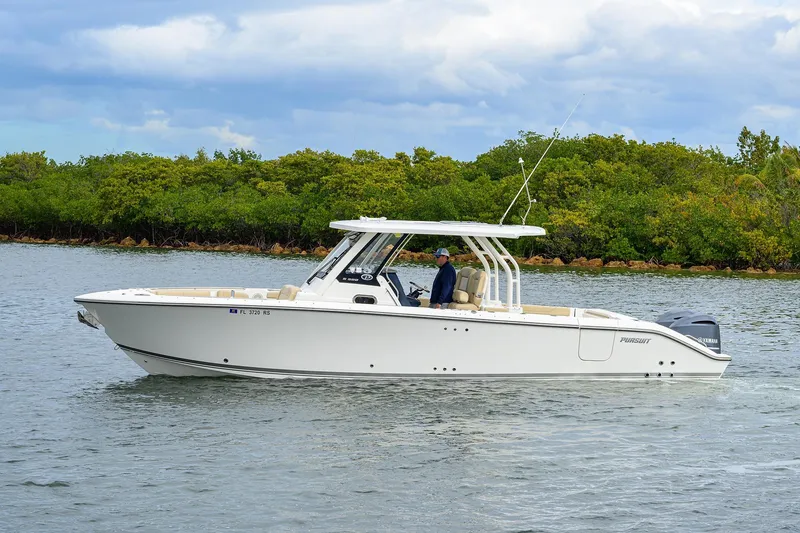 Slide: The Image of 2019 Pursuit S 328 Sport boat cruising on calm water near lush greenery. - 18