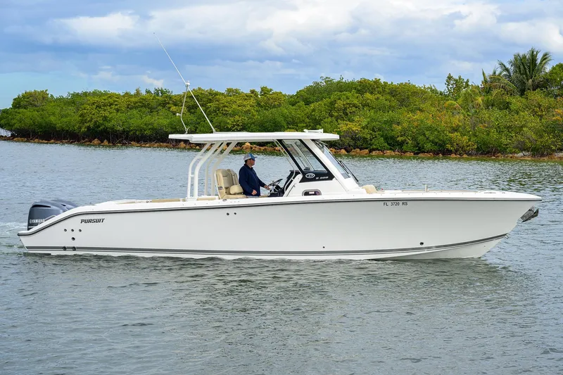 Slide: The Image of 2019 Pursuit S 328 Sport boat cruising on calm water near lush greenery. - 24
