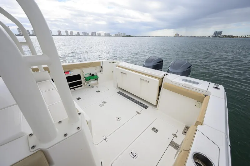 Slide: The Image of 2019 Pursuit S 328 Sport boat deck with dual engines, overlooking calm waters and city skyline. - 36