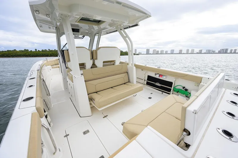 Slide: The Image of 2019 Pursuit S 328 Sport boat interior with beige seating, on a calm water backdrop. - 40