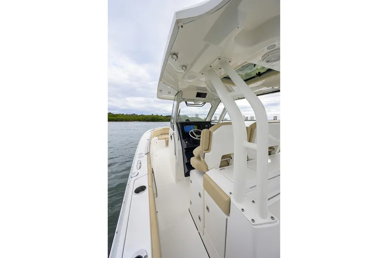 Slide: The Image of 2019 Pursuit S 328 Sport boat interior with helm and seating, on calm water. - 48