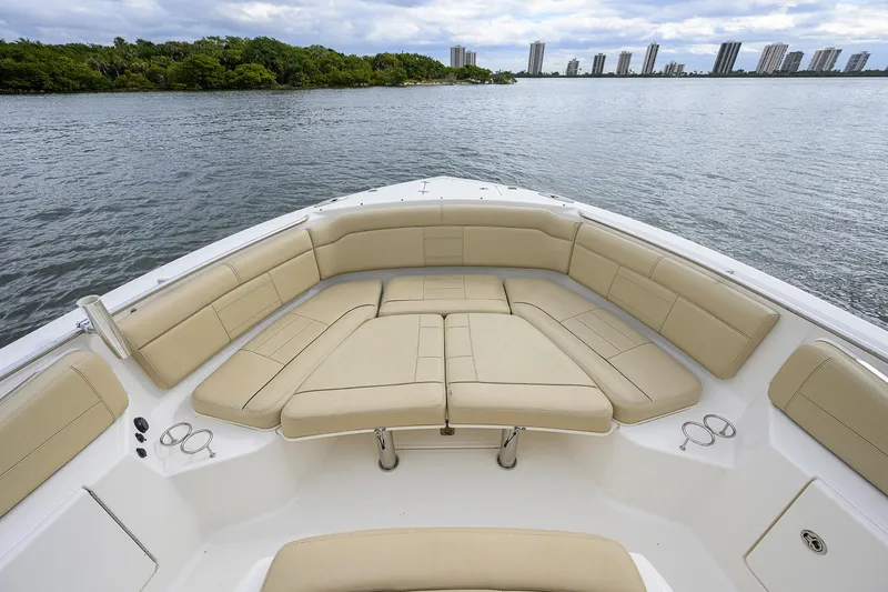 Slide: The Image of 2019 Pursuit S 328 Sport boat with spacious seating, overlooking calm waters and distant skyline. - 7