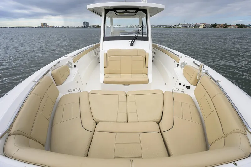 Slide: The Image of 2019 Pursuit S 328 Sport boat with spacious beige seating on calm water. - 8