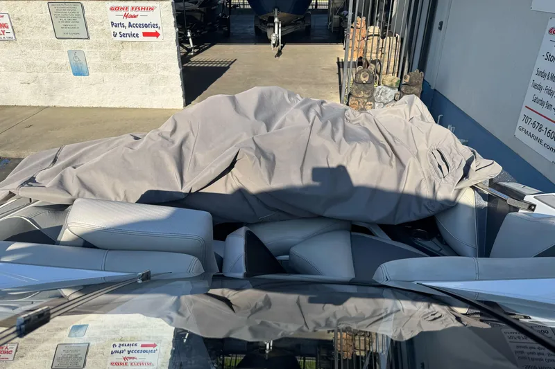 Slide: The Image of 2021 Centurion Fi23 boat interior with cover, parked near a marine service center. - 13