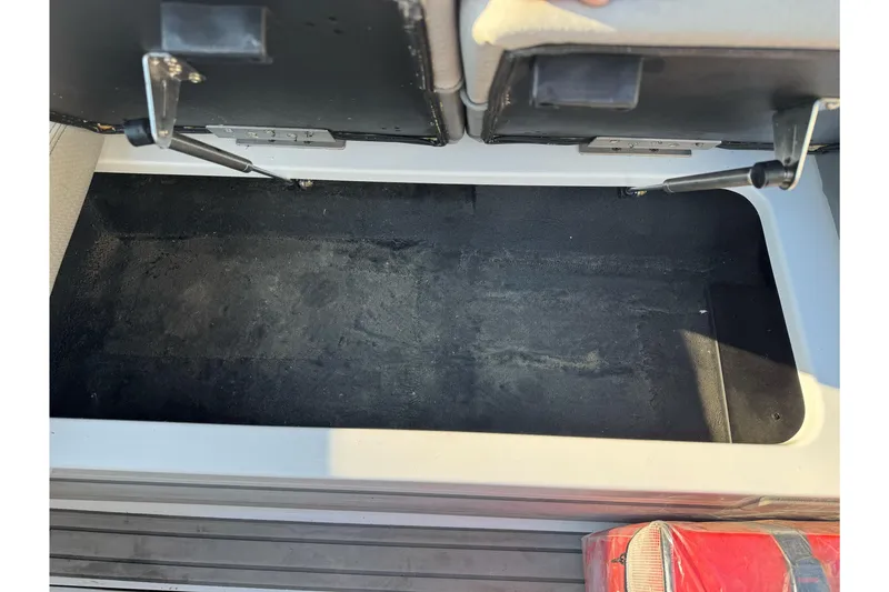 Slide: The Image of Open storage compartment in 2021 Centurion Fi23 boat, featuring black interior and hydraulic hinges. - 22