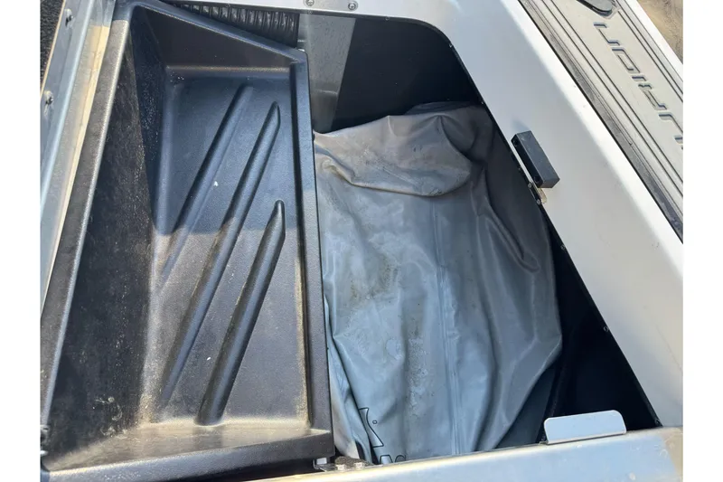 Slide: The Image of 2021 Centurion Fi23 boat storage compartment with black tray and gray cover. - 25