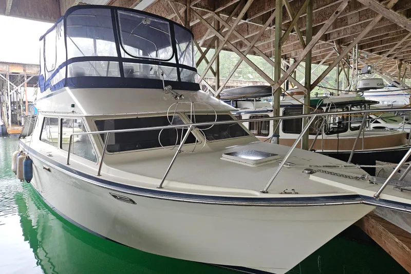 The Image of 1989 Tollycraft Sport Sedan cruising on calm water with forested background. - 0