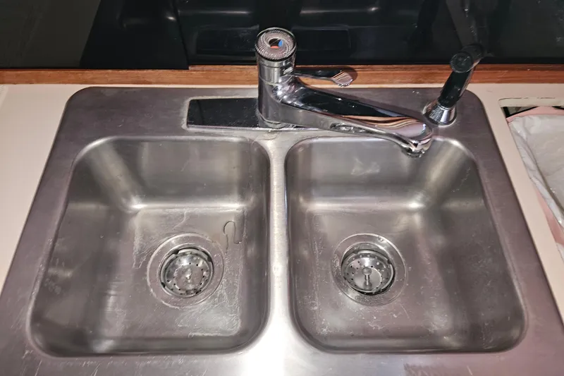 Slide: The Image of 1989 Tollycraft Sport Sedan kitchen with stove, sink, and fridge in wooden cabinetry. - 14