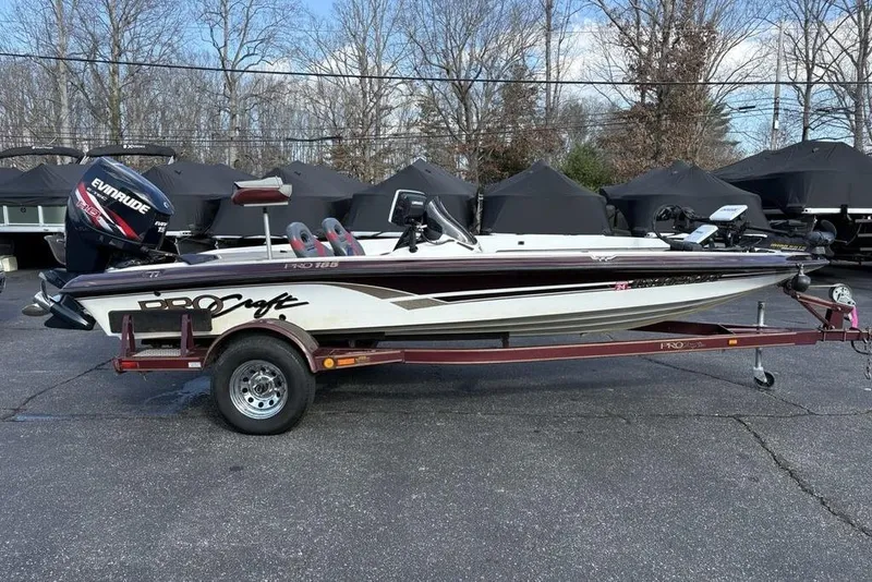 Slide: The Image of 2024 ProCraft 185 Pro boat on trailer, featuring Evinrude motor, parked outdoors. - 4