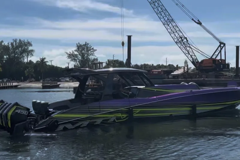 Slide: The Image of 2023 MTI 50v boat with vibrant design docked near construction site. - 3