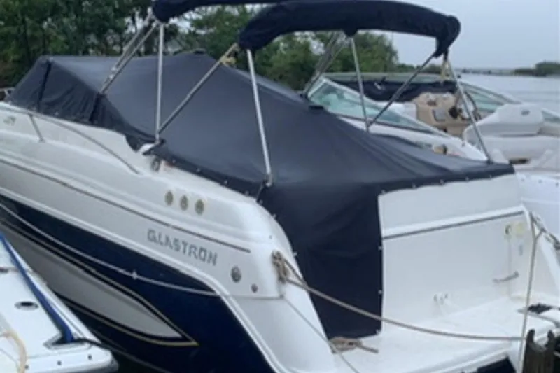 Slide: The Image of 2007 Glastron GS 279 boat with black cover docked near water. - 3