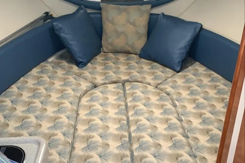 Slide: The Image of 2007 Glastron GS 279 cabin interior with patterned bedding and blue cushions. - 4