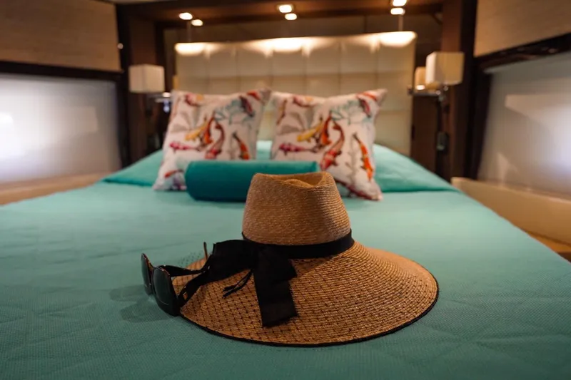Slide: The Image of Luxurious Azimut 70 yacht bedroom with straw hat and sunglasses on turquoise bed. - 14