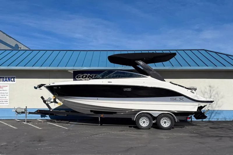 The Image of 2026 Sea Ray SLX 260 boat on trailer, parked outdoors with blue roof background. - 1